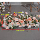 Boules de roses simulées orange et rose avec de longues rangées de fleurs disposées sur le site du mariage, décorées d'arches en fer et de fleurs simulées